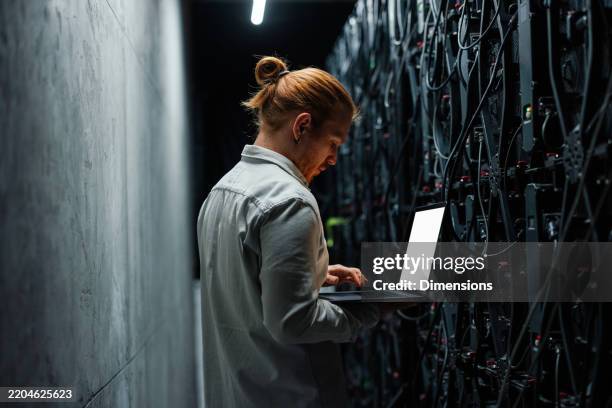it specialist working on a laptop in a server room - datacenter bildbanksfoton och bilder