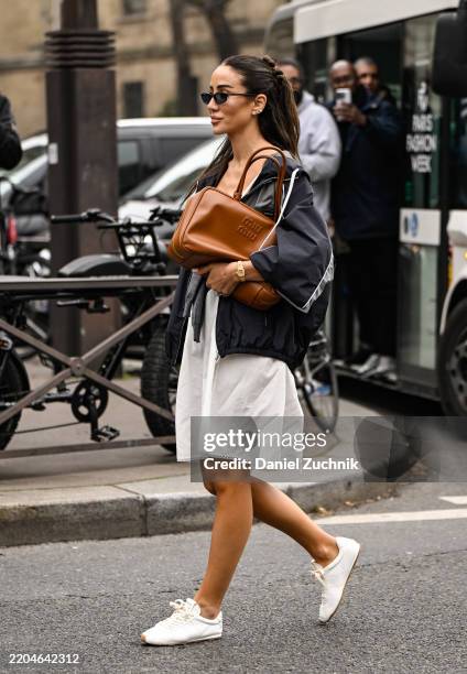 Tamara Kalinic is seen wearing a gray Miu Miu top, black Miu Miu jacket, white skirt, white sneakers and brown Miu Miu bag and black sunglasses...