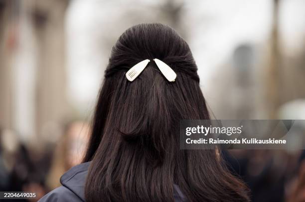 Guest wears navy blue jacket and white Miu Miu hair clips outside the Miu Miu fashion show during the Womenswear Fall/Winter 2025/2026 as part of...