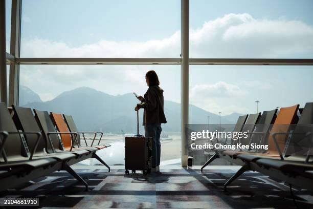 mujer asiática en la sala de espera del aeropuerto a la espera de un avión de vuelo - pasajero fotografías e imágenes de stock