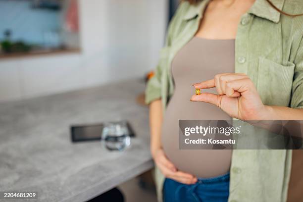 close-up of the hand of a pregnant woman holding a vitamin - omega 3 stockfoto's en -beelden
