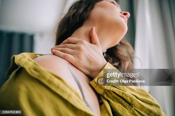 close-up of woman with hand on sore neck for pain relief - irritation cutanée photos et images de collection