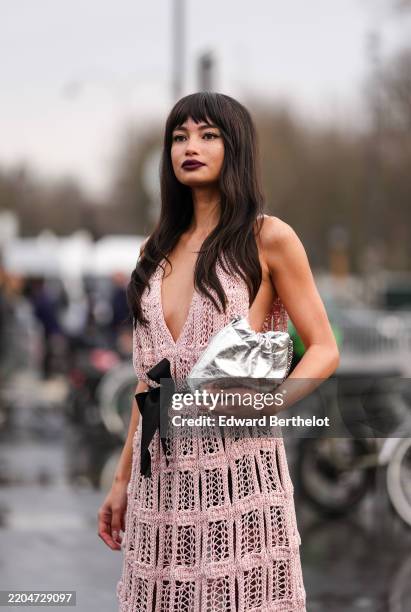 Kelsey Merritt wears black sunglasses, burgundy bordeaux lipstick, light pink sheer mesh knit plugging necklace black bow belt Chanel midi dress,...