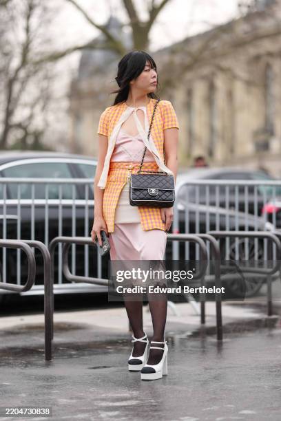 Susie Lau wears bright orange pink pattern short sleeve Chanel blazer jacket, light pink silk slip lace midi dress, shiny black quilted Chanel...