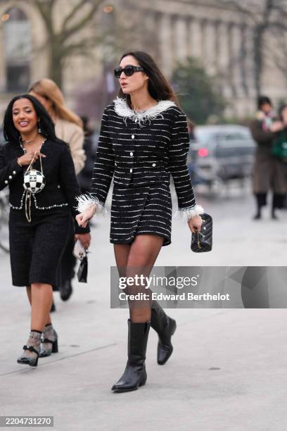 Guest wears black Chanel sunglasses, black and white tweed Chanel jacket, matching mini skirt, a black leather quilted Chanel bag, black tights,...