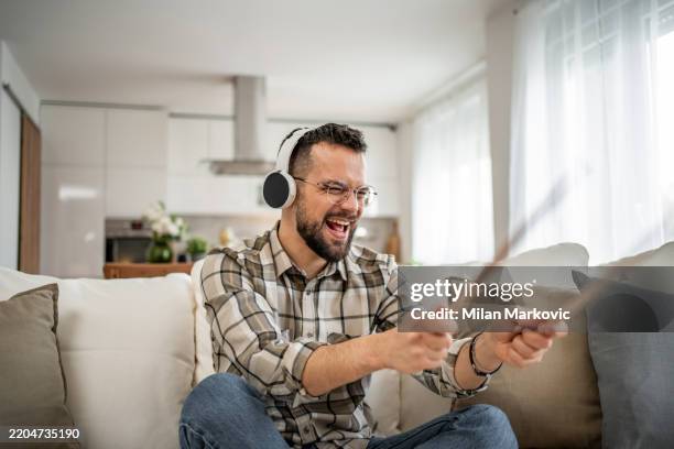 músico entusiasta que toca la batería de aire en casa con auriculares - baterista fotografías e imágenes de stock