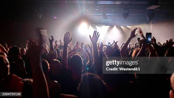 crowd enjoying illuminated live music concert at night - popular music concert stock pictures, royalty-free photos & images
