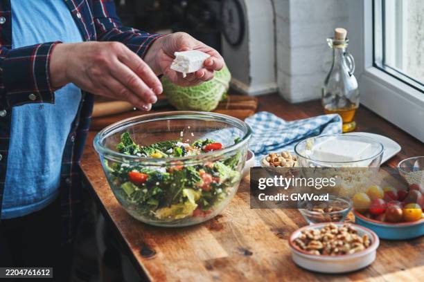 trending foods - superfoods: preparing kale, quinoa salad with tofu, tomatoes, nuts and chickpeas for a healthy meal - salad bowl stock pictures, royalty-free photos & images
