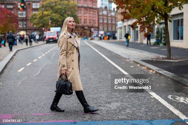 businesswoman walking across road in city - beige purse stock pictures, royalty-free photos & images
