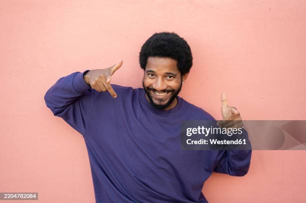 cheerful man in purple t-shirt against pink background - purple shirt stock pictures, royalty-free photos & images