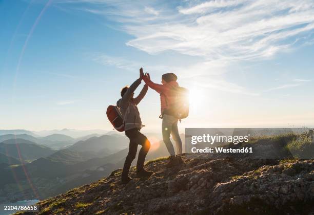 happy couple giving high five to each other on top of mountain - routard photos et images de collection