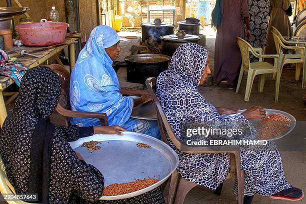 Women sift through grains at a local kitchen in the Shambat area of Khartoum North on March 16, 2025. In another war-ravaged neighbourhood of Sudan's...