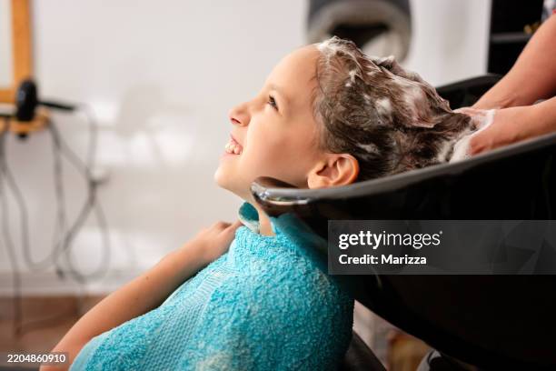 girl washes her hair with shampoo in a hairdressing salon - haar knippen stockfoto's en -beelden