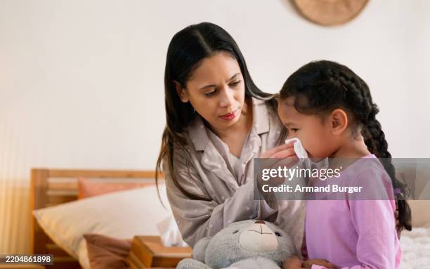 sick, help and mother with child for blowing nose on bed with cold, flu or allergies symptoms. care, tissue and mom with girl kid for sinusitis with hayfever illness in bedroom together in home. - sinusitis stock pictures, royalty-free photos & images