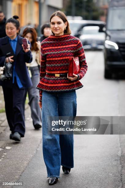 Guest wears red black and yellow printed long sleeves top with black belt, blue jeans, red bag, outside Ferragamo, during the Milan Fashion Week...