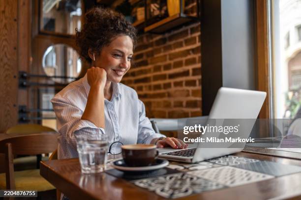 businesswoman working on laptop in cafe, enjoying coffee and staying connected - flexible screen stock pictures, royalty-free photos & images