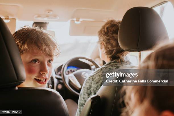 a little boy glances behind him in a car interior - carsharing stock-fotos und bilder