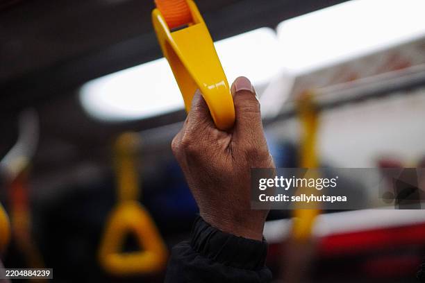 hand holding grab handle in train or bus - afferrare foto e immagini stock