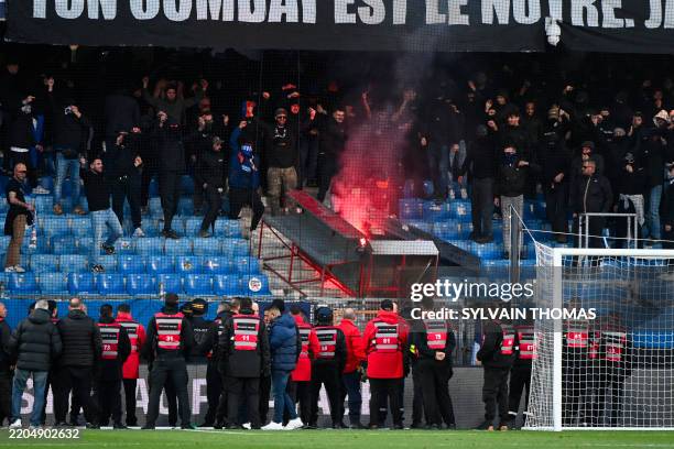 Montpellier's supporters light flares in front of stadium security staff members during the French L1 football match between Montpellier Herault SC...