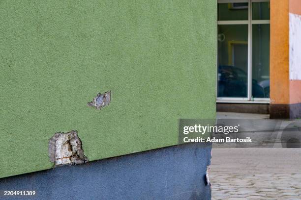 damaged and chipped facade of apartment block. damage to plaster for insulation. styrofoam protruding from the wall.