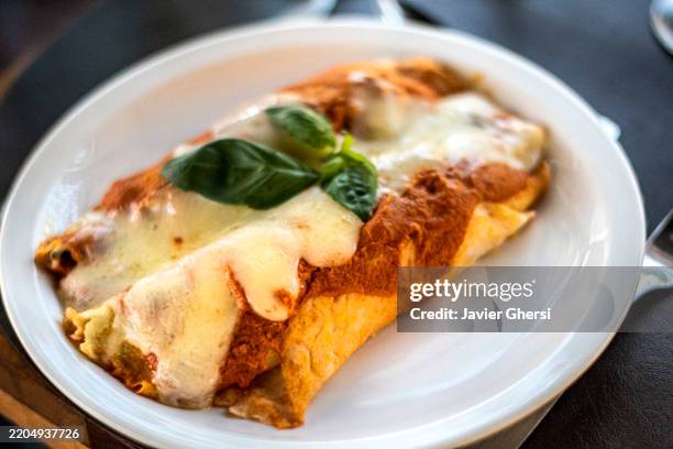 stuffed cannelloni covered with tomato sauce and cheese. homemade pasta. - beef cannelloni stock pictures, royalty-free photos & images