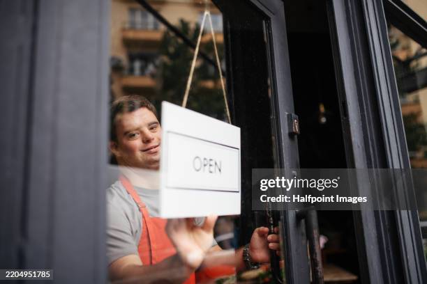 young man with down syndrome working as an assistant in a small flower shop. - gelijkheid stockfoto's en -beelden