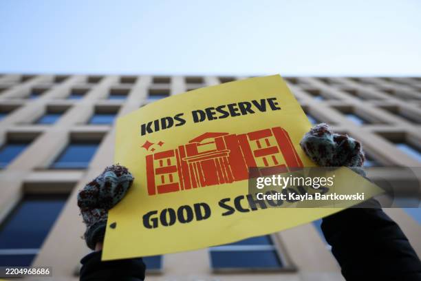 Community member holds a sign during a rally in front of the Department of Education to protest budget cuts on March 13, 2025 in Washington, DC. On...