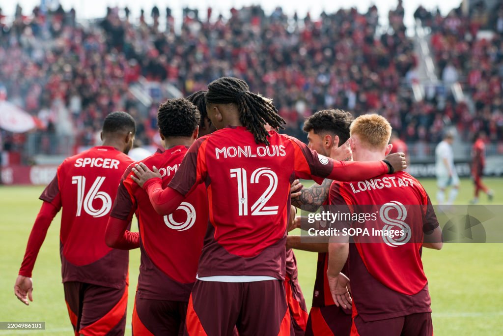 Zane Monlouis #12 (C) celebrates with teammates after...