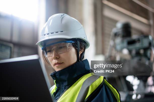 aisan female working on laptop in factory - aisan women stock pictures, royalty-free photos & images
