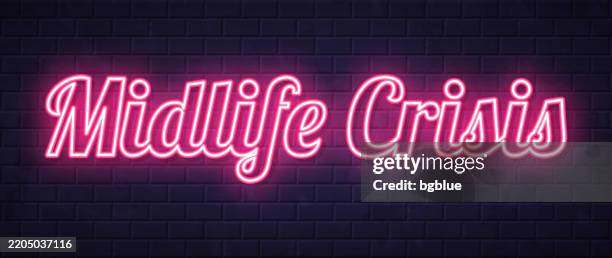midlife crisis - glowing neon text on brick wall background - menopause stock illustrations