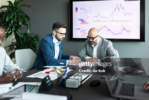 Business professionals analyzing data in a meeting with charts and reports displayed Business professionals analyzing data in a meeting with charts and reports displayed