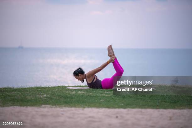 la donna pratica yoga all'aperto vicino all'oceano durante il crepuscolo, in equilibrio in un grazioso piegamento all'indietro. - piegarsi allindietro foto e immagini stock