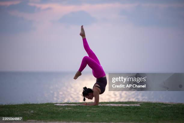 la donna pratica yoga all'aperto vicino all'oceano durante il crepuscolo, in equilibrio in un grazioso piegamento all'indietro. - piegarsi allindietro foto e immagini stock