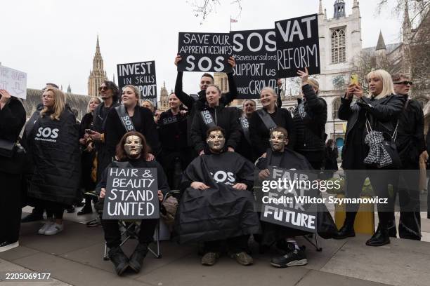 Hairdressers, barbers and beauty professionals wearing black cutting gowns and uniforms stage a rally outside Houses of Parliament calling on the...