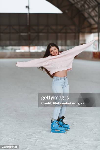 overjoyed woman skating on empty ice rink smiling and spreading her arms - ice skater stock pictures, royalty-free photos & images