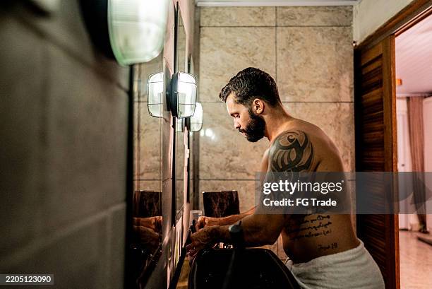 uomo adulto medio che indossa un asciugamano sul bagno di casa - metrosessuale foto e immagini stock