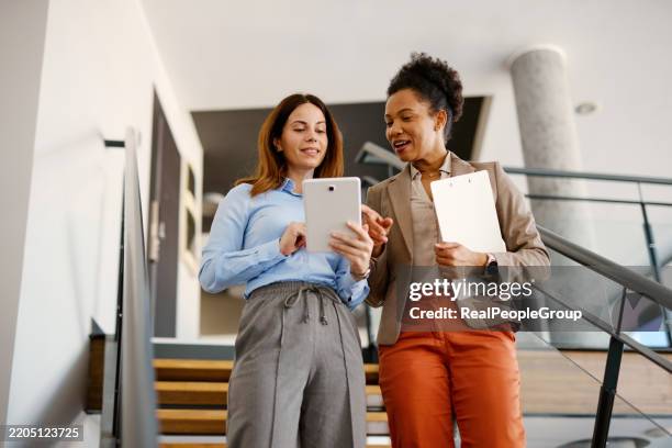 businesswomen walking and discussing using a digital tablet in modern office - using tablet screen stock pictures, royalty-free photos & images