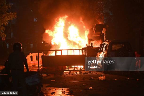 Firefighter stands near the burning vehicles set on fire following clashes at the Chitnavis Park Square area, in Nagpur on March 17, 2025. Nine...