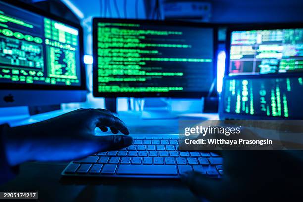 close-up of programmer hands typing amid multiple computer monitors - computer crime stock pictures, royalty-free photos & images