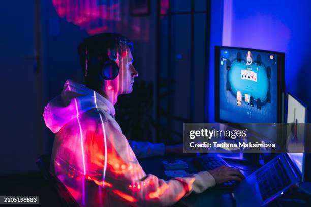 a mid adult man playing poker online. neon light. - vício imagens e fotografias de stock