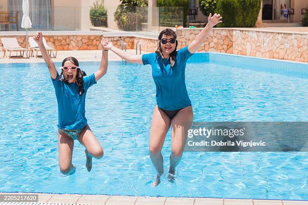 girls holding hands when jumping into swimming pool - young girl jumping into swimming pool stock pictures, royalty-free photos & images
