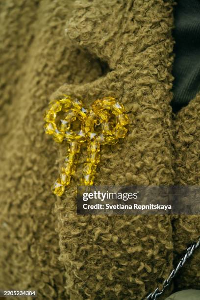 yellow crystal bow brooch attached to a fluffy green coat - brooch stock pictures, royalty-free photos & images