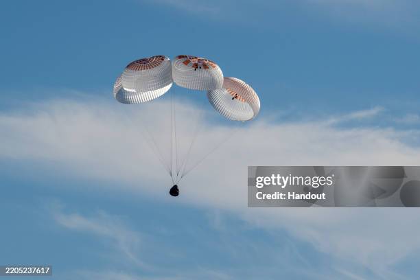 In this handout image provided by NASA, A SpaceX Dragon spacecraft is seen as it lands with NASA astronauts Nick Hague, Suni Williams, Butch Wilmore,...
