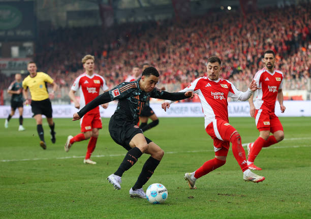 Jamal Musiala of Bayern Munich runs with the ball inside the penalty area whilst under pressure from Josip Juranovic of 1.FC Union Berlin during the...