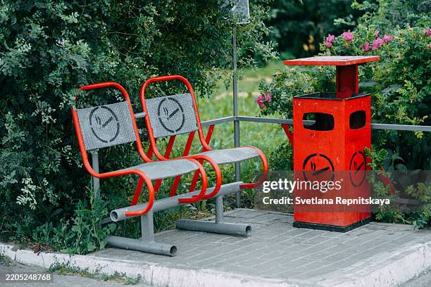 designated smoking area with bench and trash can in a park - cendrier photos et images de collection