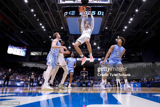 Miles Byrd of the San Diego State Aztecs dunks over members of the North Carolina Tar Heels during the First Four round of the 2025 NCAA Men's...