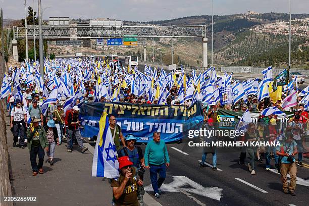 Israelis holding national flags march into Jerusalem during a demonstration against Prime Minister Benjamin Netanyahu and calling for an end to the...