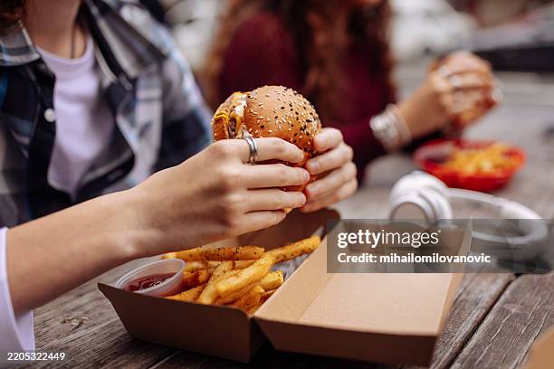 close up of teenager's hands hodling burger - snabbmat bildbanksfoton och bilder