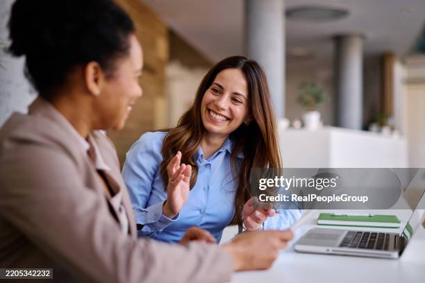 dos empresarias discutiendo alegremente en la oficina - oficio de ventas fotografías e imágenes de stock