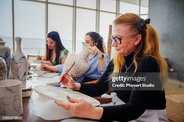 a group of people of different races and ages take part in a tile painting therapy class - fine china plate stock pictures, royalty-free photos & images